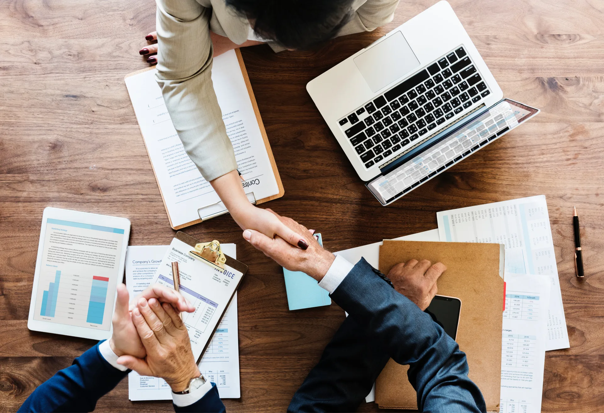 Overhead view of businesswoman and businessman shaking hands over a contract, symbolizing partnership and agreement